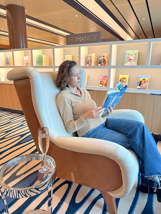 Ashley Wali relaxes with a glass of champagne and a book in the library on board the Holland America Line MS Rotterdam.