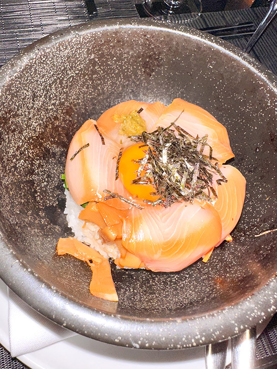 Ishiyaki buri bop (yellowtail sashimi and rice) served on a black plate at Morimoto by Sea, a restaurant on board the MS Rotterdam.