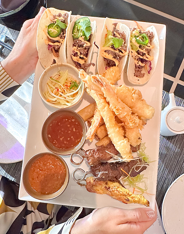 A plate of appetizers including skewers, tempuri prawns, and tacos served at Tamarind, one of the restaurants on board the MS Rotterdam.