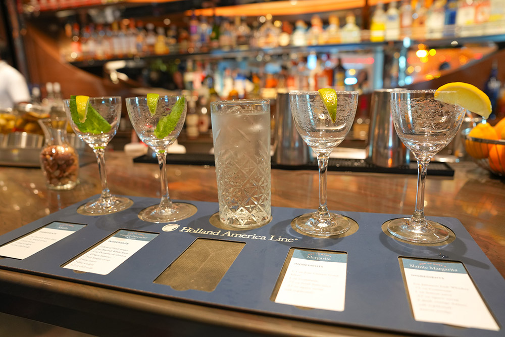 A row of cocktails glasses lined up on a bar, ready for a mixology class on the MS Rotterdam.