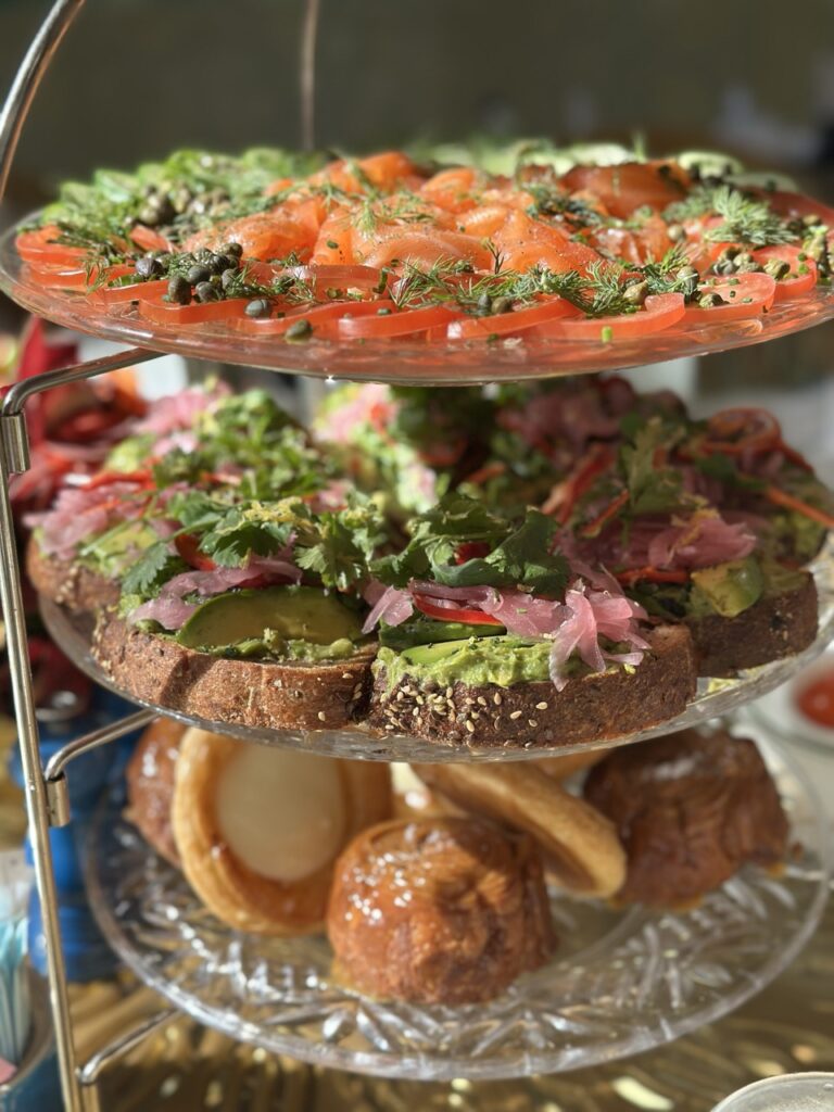The three-tier brunch tower at the Garden Table at the Bellagio, Las Vegas. The top tier is laden with smoked salmon and thin slices of cucumber and tomatoes. The second tier is filled with slices of avocado toast, and the bottom tier holds dainty breakfast pastries.
